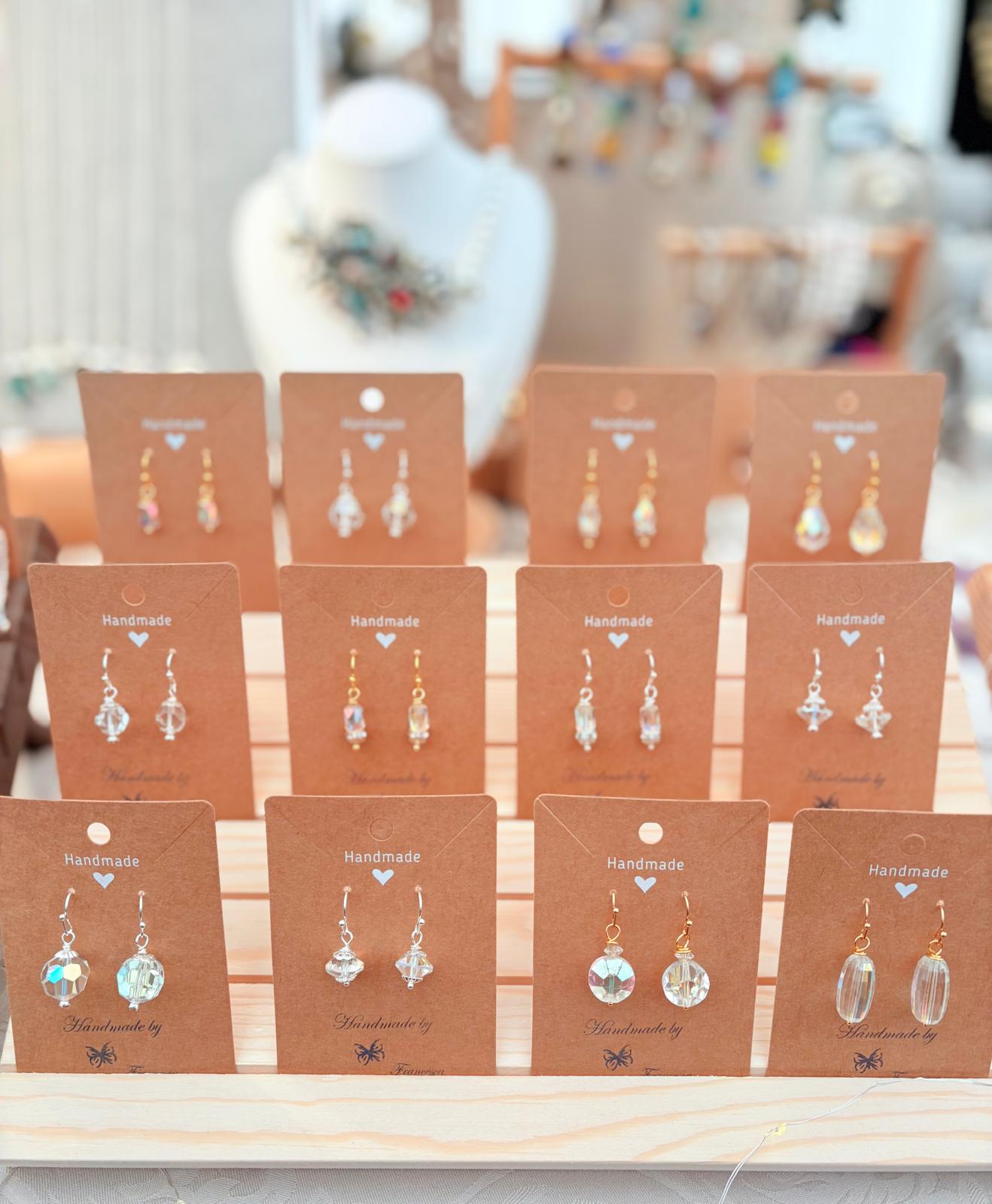 Twelve pairs of handmade crystal drop earrings displayed on cards