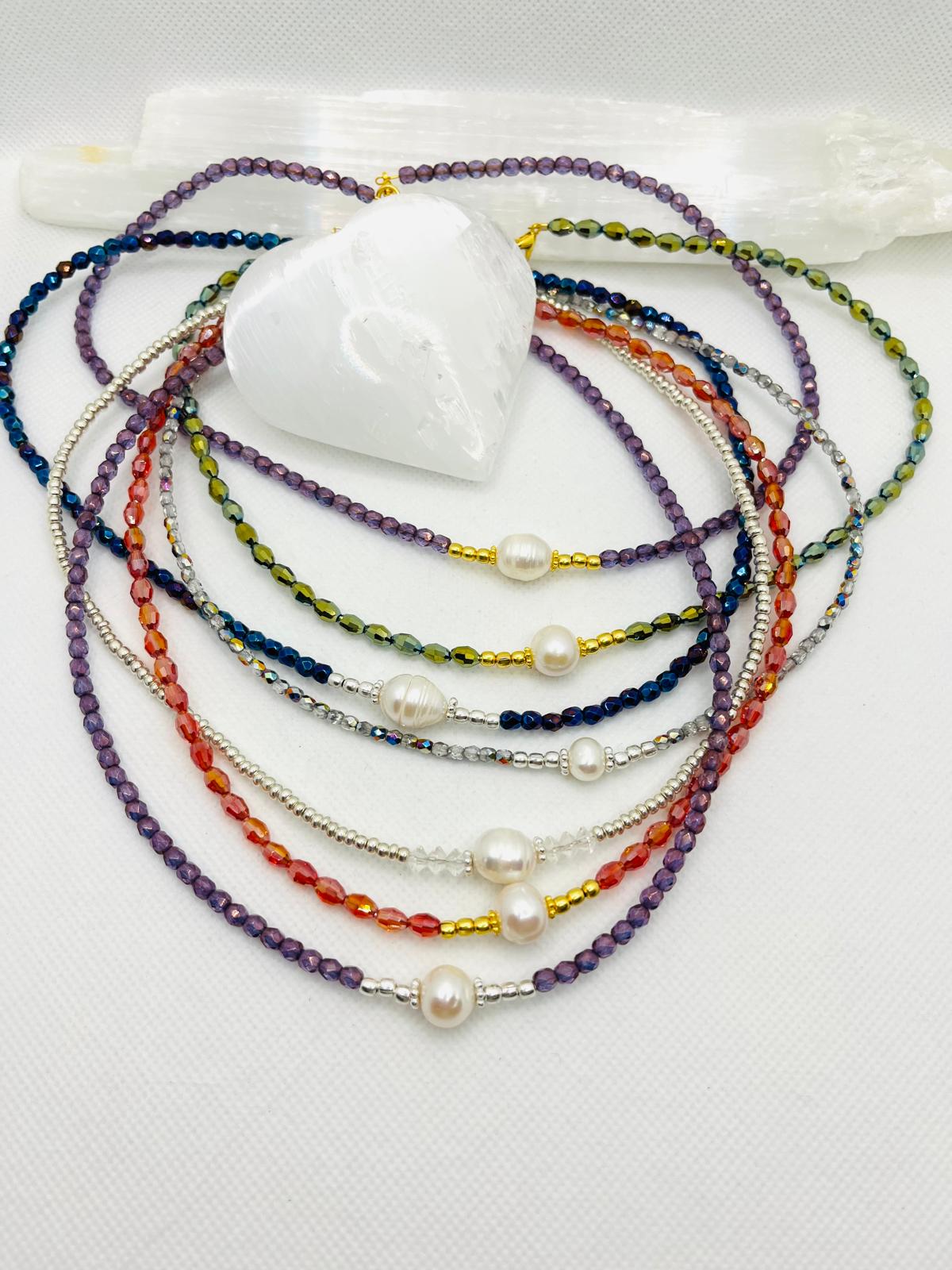 Layered pearl and gemstone necklaces with dragonfly charm, hanging on display