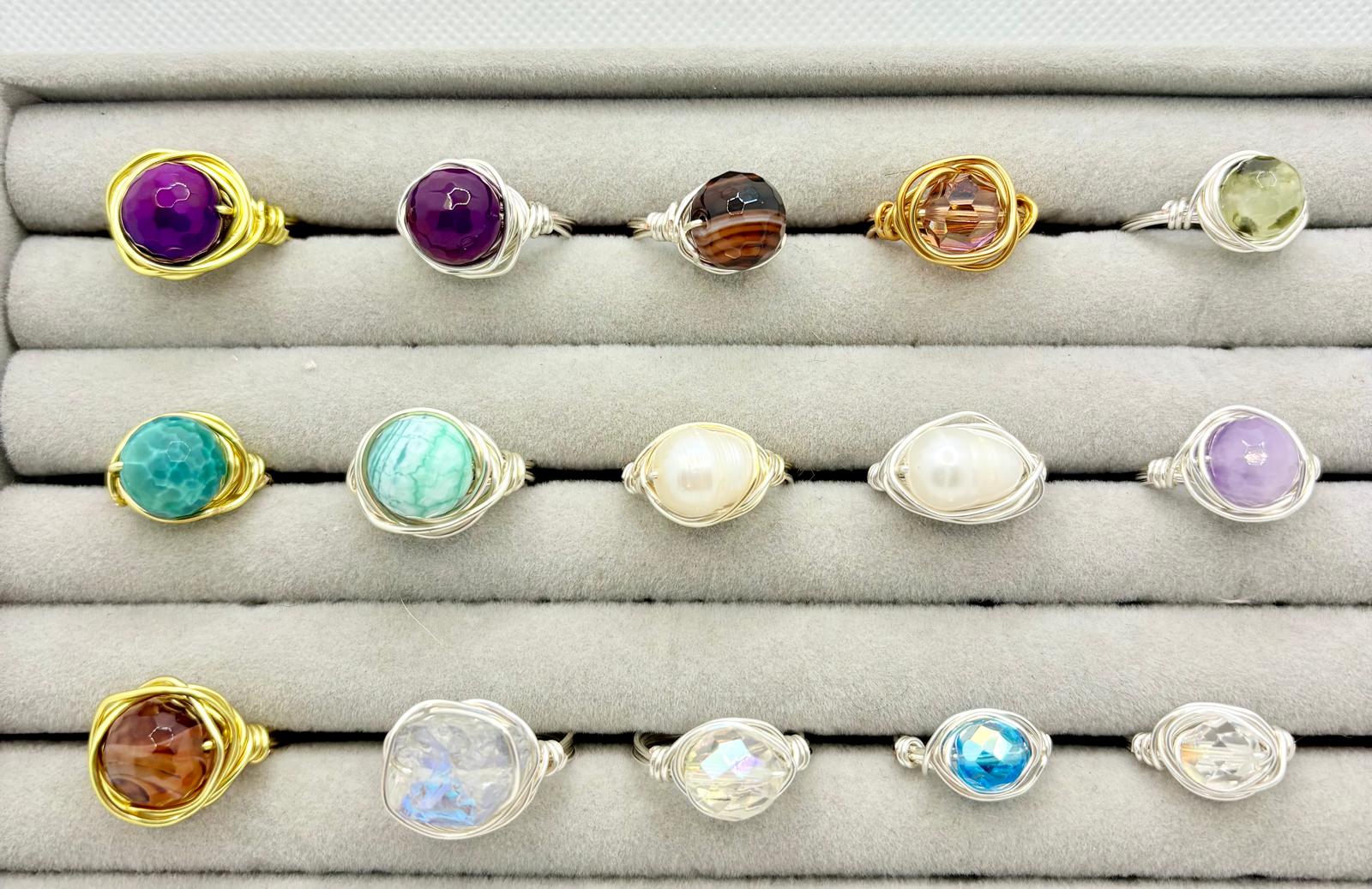 Collection of wire-wrapped gemstone rings in gold and silver wire